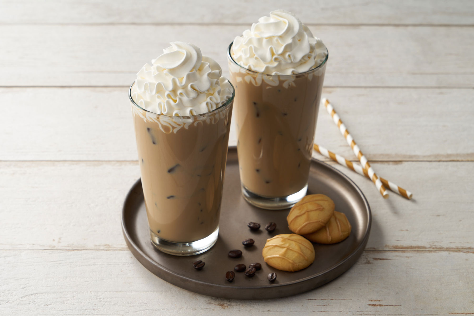 Two drinks with whipped cream and cookies on a tray