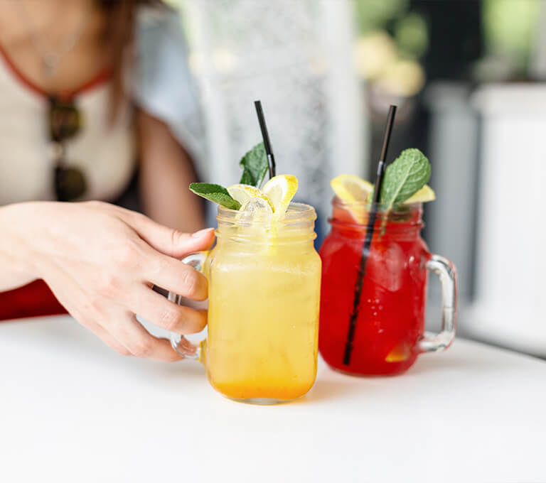A woman sitting at a table with two drinks in front of her