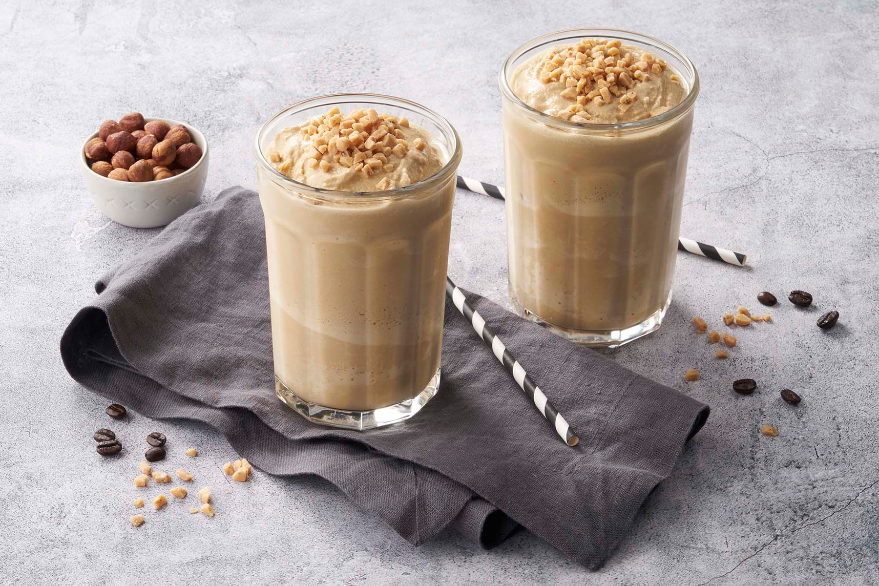 Two glasses of coffee on a table with nuts