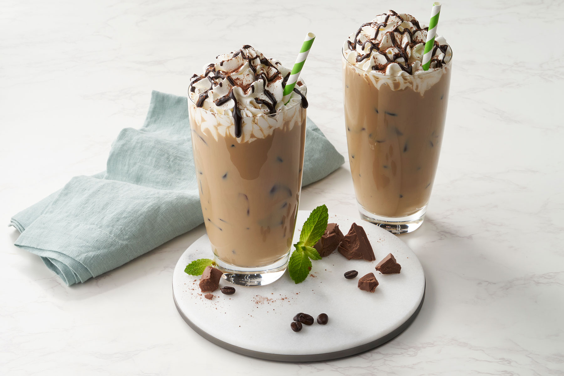 Two glasses of chocolate milkshakes on a plate