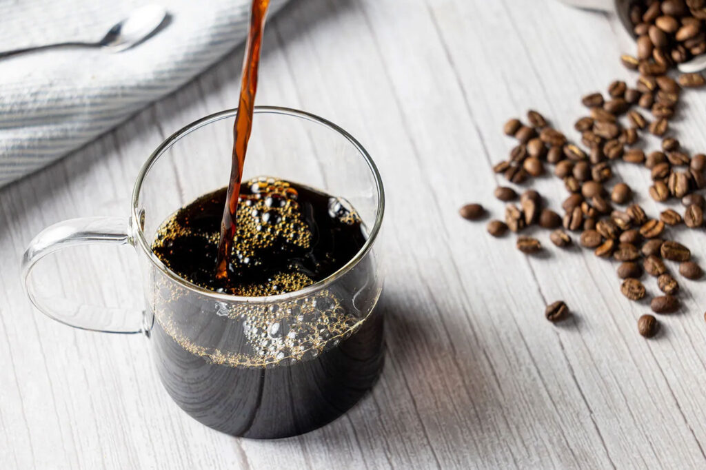 cup of coffee being poured into it as a beverage