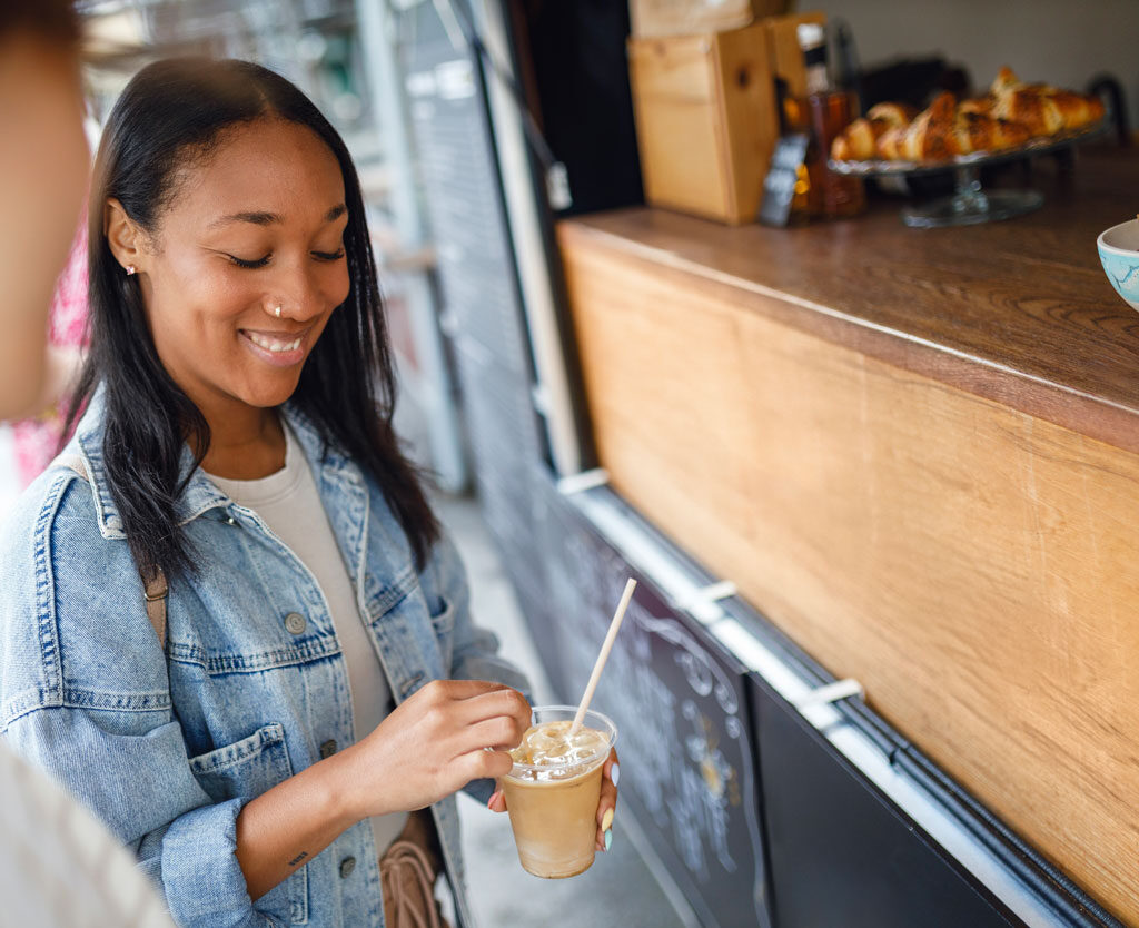 woman is smiling and holding a beverage