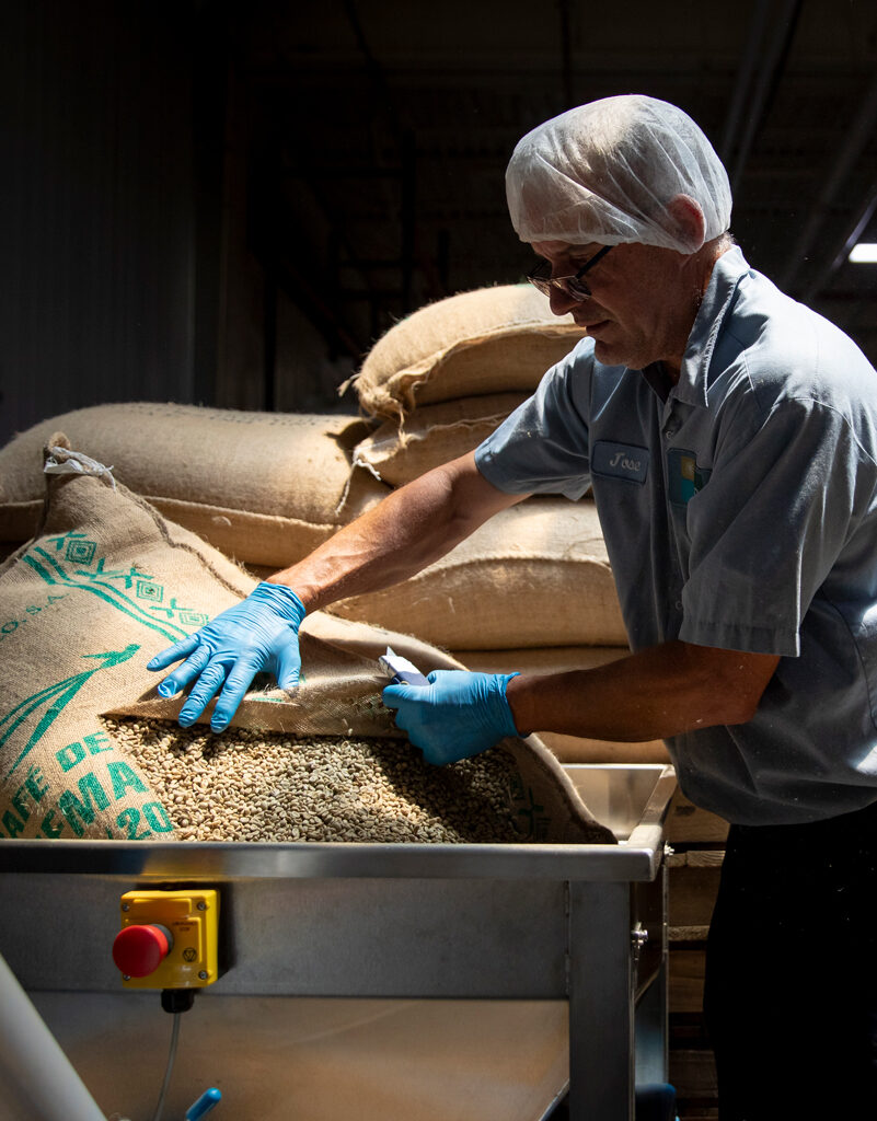 man in a blue shirt and blue gloves involved in beverage manufacturing